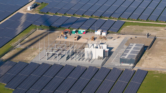 Aerial view of Zonnepark Eekerpolder with rows of solar panels, an electrical substation, and maintenance equipment in Scheemda, Groningen, Netherlands.
