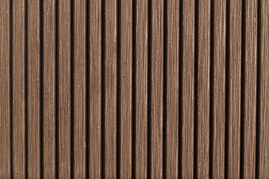 Close-up of brown composite decking boards texture with vertical grooves. Top view of wood plastic composite (WPC) material for outdoor flooring, patio, or terrace design.