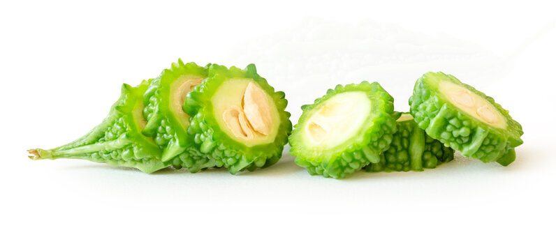 Side view of green bitter gourd or bitter melon in slices in circle shape in small pile isolated on white background with clipping path