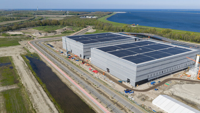 Aerial view of the JYSK DCL construction site featuring large industrial warehouses with solar panels on the roofs near the coast in Lelystad, Flevoland, Netherlands.