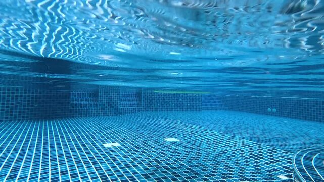 Underwater perspective of a blue tiled swimming pool, dynamic clear water motion captured in cinematic footage.
