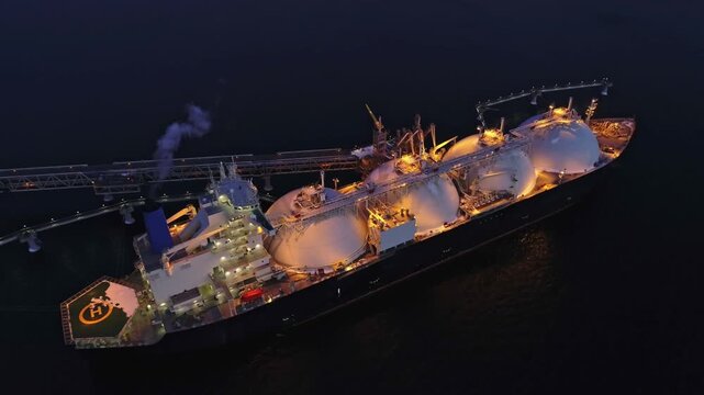 Aerial of Liquified Natural Gas LNG carrier moored to a small gas terminal at night. Fuel crisis. Sanctions
