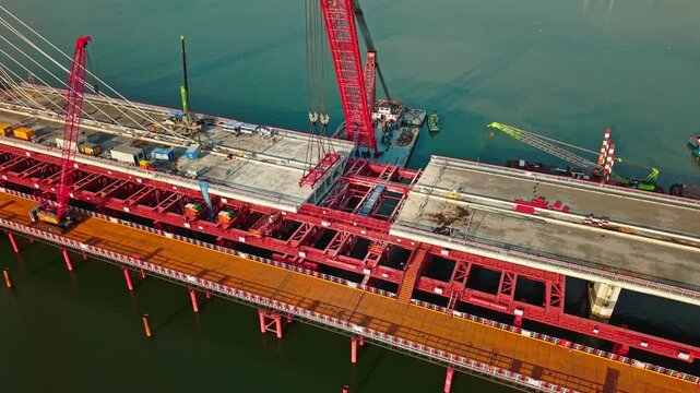 Aerial view of cranes and construction equipment are working to dismantle an old cable stayed bridge.