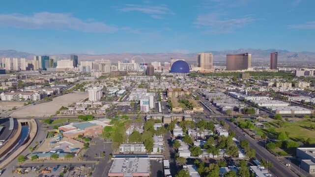 Aerial sideways dolly shot of Las Vegas suburbs and Strip skyline and mountains 