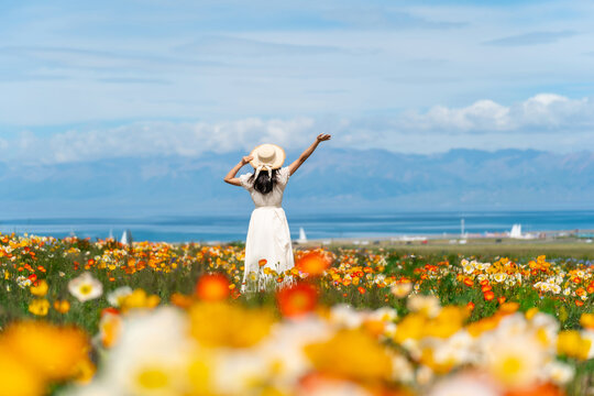 Young woman traveler relaxing and enjoying at beautiful blooming poppy flower fields at sayram lake in Xinjiang, China