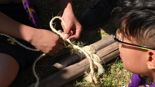 young scouts tying knots in sticks