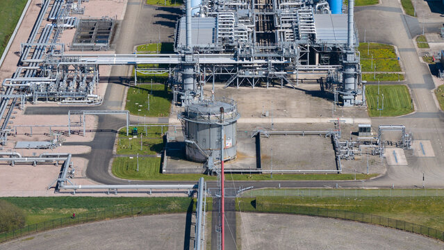 Aerial view of UGS Norg gas storage facility with an intricate network of silver pipes, large storage tanks, and industrial infrastructure in Langelo, Drenthe, Netherlands.