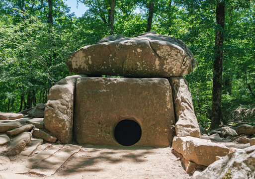Prehistoric megalithic tomb made of massive stone blocks hidden deep within a vibrant summer forest