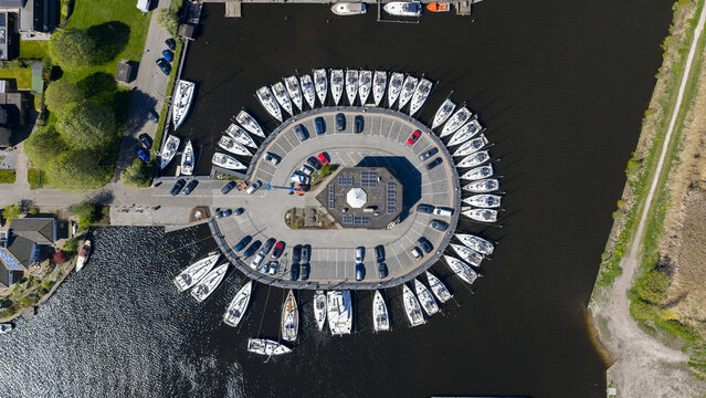Aerial view of Enjoy Sailing Zeiljachtverhuur marina featuring sailboats docked in a circular pattern around a central parking area in Lemmer, Friesland, Netherlands.