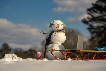 Obraz premium Snowman online freelancer scene in winter. Winter online shopping. Remote online work winter concept. Snowman freelancer with laptop in snow. Creative winter snowman with computer setup.