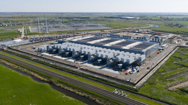 Aerial view of Datacenter Westpoort featuring its large industrial structure with cooling units surrounded by green fields and railway tracks in Groningen, Groningen, Netherlands.