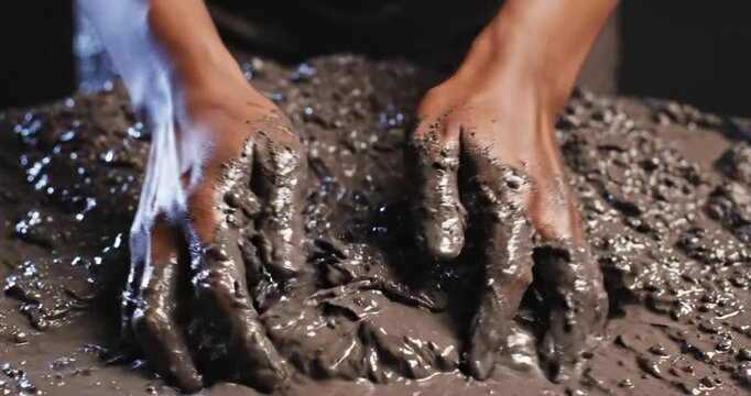 Hands mixing wet concrete in a construction setting, showcasing texture and preparation process
