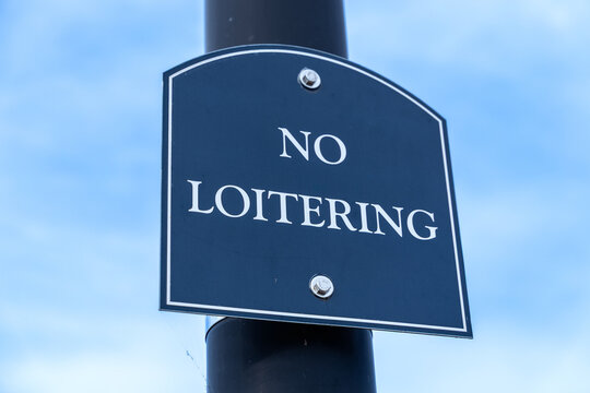 Blue No Loitering Sign on Black Pole Against Blue Sky