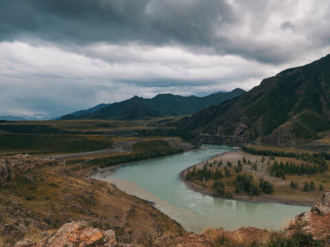 Katun and Chuya rivers join in the Altai Mountains, displaying striking color differences on an overcast day