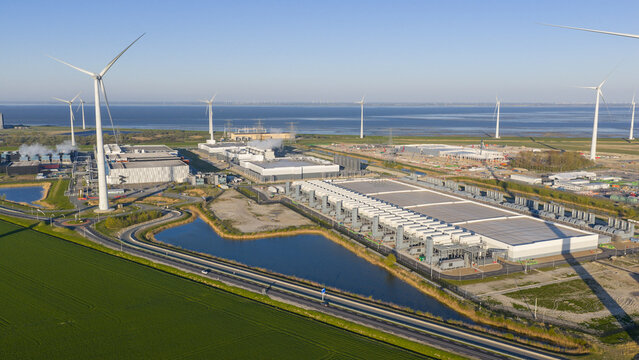Aerial view of the Google GRQ data center surrounded by wind turbines and green fields in Eemshaven, Groningen, Netherlands.