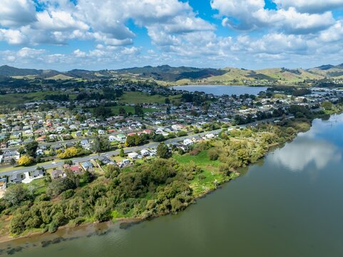 Aerial view of a residential area in Huntly, New Zealand, showcasing the town's layout, proximity to the river, and the surrounding landscape.