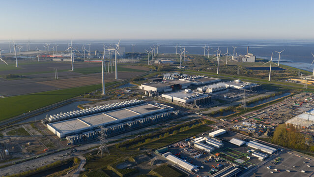 Aerial view of the Google data center and a large wind farm with numerous turbines along the coast in Eemshaven, Groningen, Netherlands.