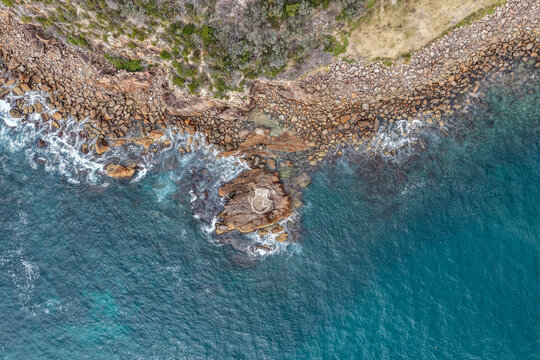 Aerial view of World War II gun emplacement at Tomaree Head in New South Wales, Australia surrounded by rugged rocky coastline and turquoise ocean water. 