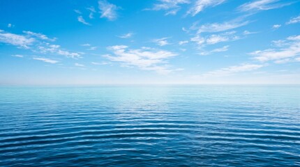 Obraz premium Calm blue sea water and bright sky with white clouds at sunny day