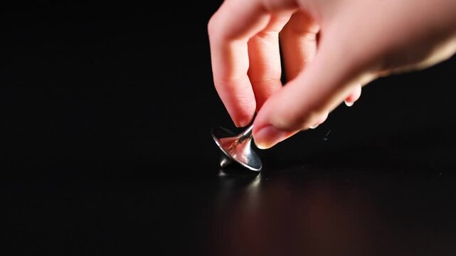 Spinning metal tops on black background in motion video footage showing multiple colors including silver gold and bronze.