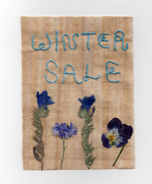 Winter Sale Text in Blue Thread on Papyrus Texture with Blue Pressed Flowers, Mixed Media Social Media Graphic