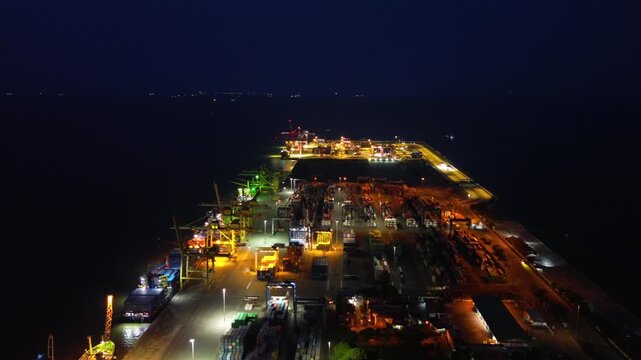 Aerial view of container port at night with illuminated cargo terminal and logistics operations