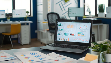 Fototapeta premium Modern Office Workspace with Laptop Showing Business Analytics Charts – Corporate Data Analysis Concept