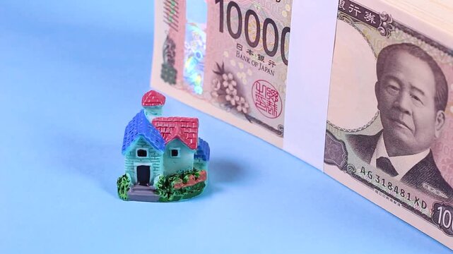 新紙幣の札束とミニチュアハウスの回転動画