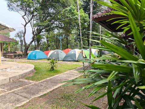 A serene campsite nestled among trees with colorful tents