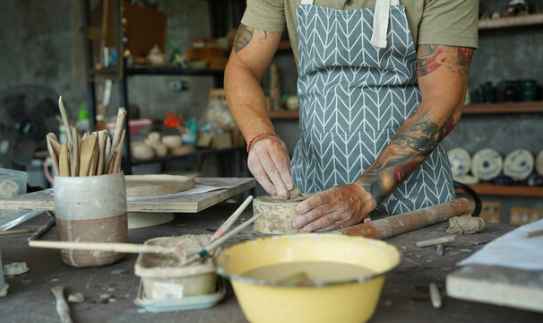 An adult man makes a ceramic plate in a workshop