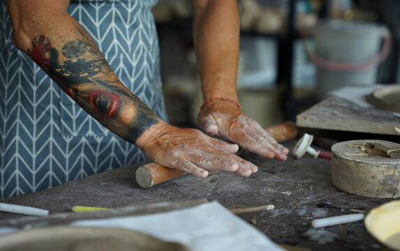 An adult man makes a ceramic plate in a workshop