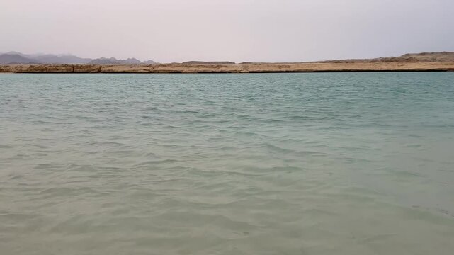 Crystal clear turquoise waters of the Red Sea with desert coast in the background