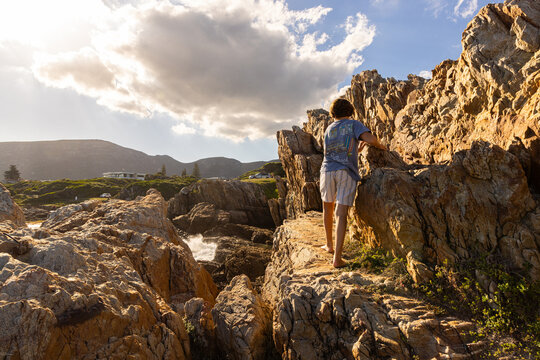 boy exploring Kammabaai Beach, Hermanus, South Africa at sunset