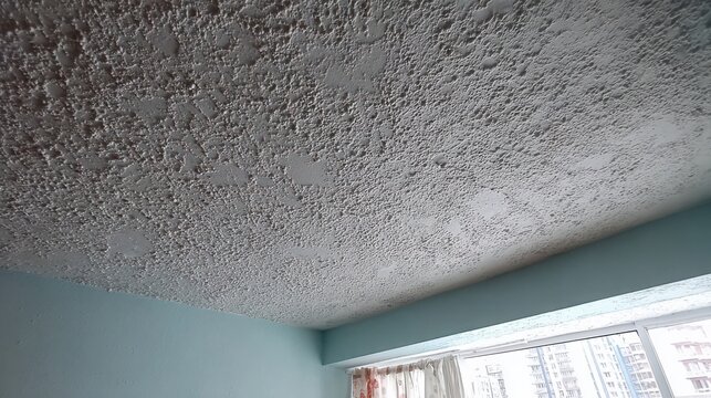 Light grey popcorn textured ceiling with subtle variations in pattern and light, showcasing interior architectural detail