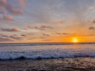 Sunset over the mighty Pacific Ocean in Carlsbad with birds in the sky and the sun setting on the right. © Bryan Lambert