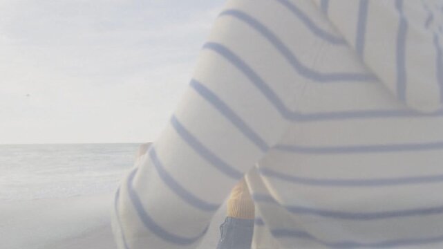 Smiling woman looking back, leading partner toward ocean while camera moving closer then receding
