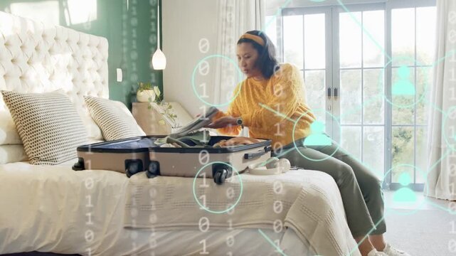 Mature woman opening suitcase and packing for travel on bed, binary overlay appearing around phone