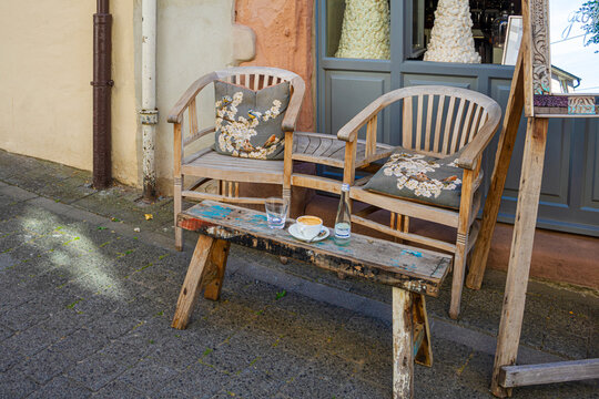 Rustic wooden seating in front of a caf&eacute; on the sidewalk in an old town