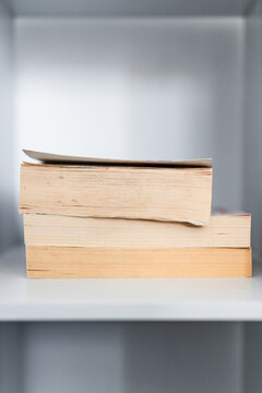 stack of old books on minimalist white bookshelf shallow depth of field