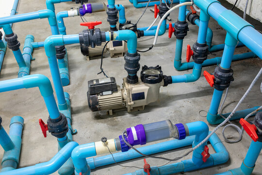 Water pump system for swimming pool with blue pvc pipes and red valves in technical room