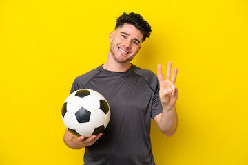 Handsome young football player man isolated on yellow background happy and counting three with fingers © luismolinero