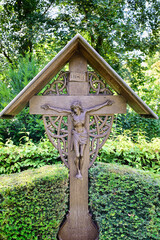 schönes Holzkreuz mit Dach und dem gekreuzigten auf einem Friedhof in Köln © Blende8