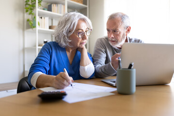 Senior couple doing home finances using laptop and calculator © Daniel