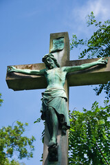 Großes Steinkreuz mit Jesus unter blauem Himmel auf einem Friedhof in Köln © Blende8