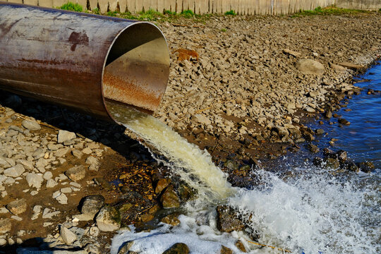 Sewage pipe discharging wastewater into river, environmental pollution, dirty water flowing from drainage outlet