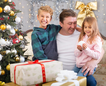 Happy father with son and daughter near the Christmas tree in living room. Merry Christmas