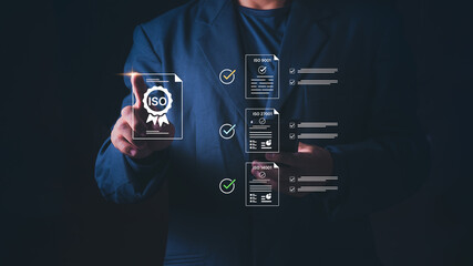 Concept of quality management, information security, environmental standard, and business compliance audit, Businessman pointing at virtual ISO certification icons for ISO 9001, 27001, and 14001. © 418 House
