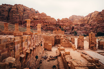 Obraz premium Ancient ruins and stone columns of the Great Temple overlooking the mountains in Petra, Jordan.