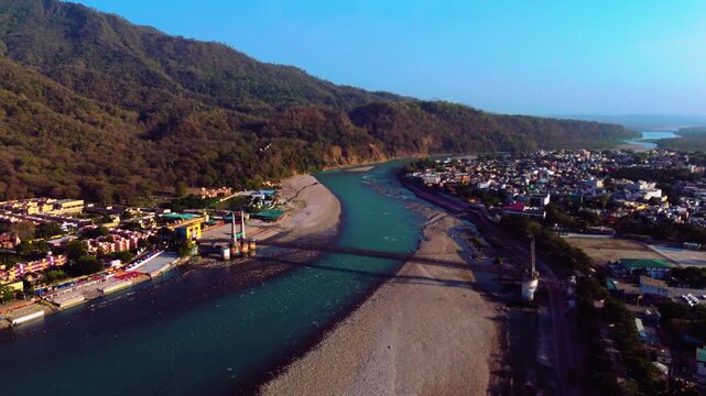 Beautiful aerial view of Ganga river with Jhula bridge and surrounding green mountains in Rishikesh.