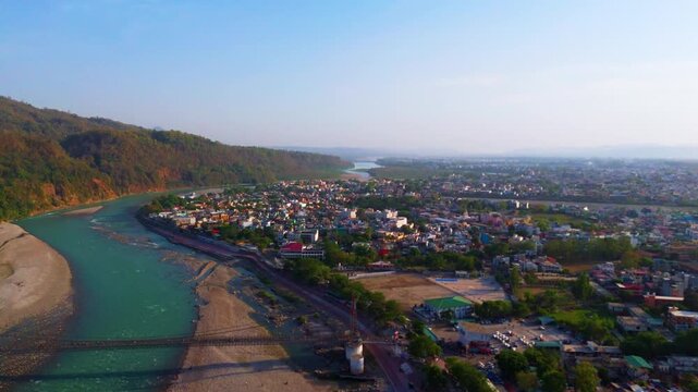 drone shot of Rishikesh capturing the Ganga river flowing through hills and the famous Jhula suspension bridge.